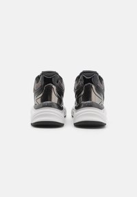 Black and white sneakers with glossy accents, mesh panels, and padded collar. Notable logo and thick, cushioned sole for comfort.