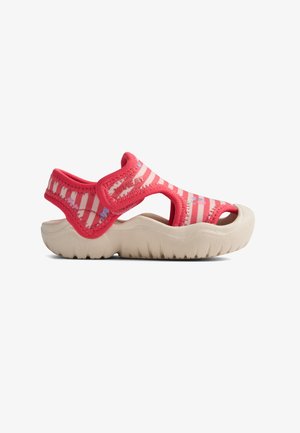 Růžovo-bílé pruhované sandály s gumovou podrážkou, výřezy po stranách a nastavitelným páskem. Měkký materiál s květinovými zdobeními a texturovaným povrchem.