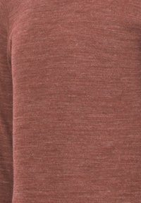 Rød striktrøje med en blød, tekstureret finish, der har en let tætsiddende silhuet og subtile variationer i stoffarven.