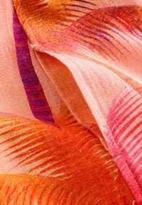 Stof met oranje, roze en paarse tinten, met een patroon van gebogen lijnen en een gevouwen naad.