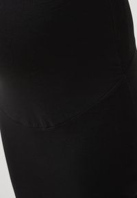 Čierna tehotenská sukňa s hladkou textúrou, vysokým pásom a elegantným strihom. Materiál je elastický pre pohodlie.