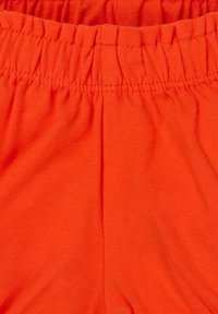 Jasnopomarańczowa bawełniana tkanina o miękkiej teksturze, z elastycznym pasem i marszczonymi szwami, zapewniającymi regulowane dopasowanie.