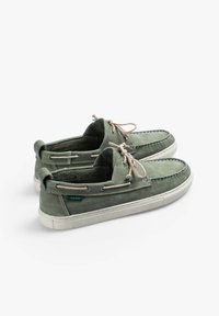 Scarpe da barca in pelle verde con finitura testurizzata, design con lacci e suola bianca a contrasto. Presenta un'etichetta di branding sul lato.