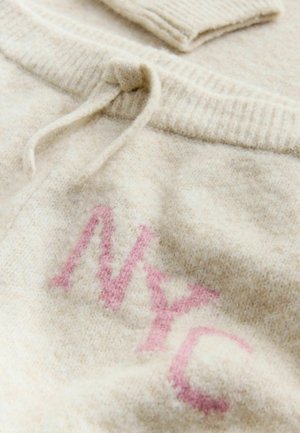 Cremefarvet sweater med en blød tekstur, med et lyserødt strikket "NYC" logo, rund halsudskæring og snøre detalje i kanten.