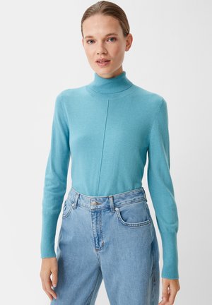 Light blue turtleneck sweater in soft knit material with long sleeves and a vertical seam detail, paired with high-waisted light denim jeans.