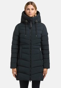 Giacca piumino nera con colletto alto, chiusura con zip, due tasche anteriori e design trapuntato angolato. Presenta cordini nel cappuccio.