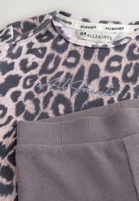 Langærmet top med leopardprint i blød stof med ribbet tekstur, parret med grå ribbede bukser med elastisk talje.