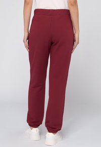 Bordeaux joggers met een rekbare tailleband, taps toelopende boorden en zachte stof. Combinatie met witte sneakers voor een casual look.