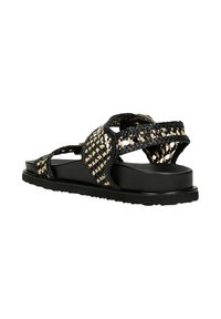 Geflochtene schwarze und braune Sandalen mit einer dicken schwarzen Sohle, die über Kreuz geschnallte Riemen und eine strukturierte Oberfläche im oberen Teil aufweisen.