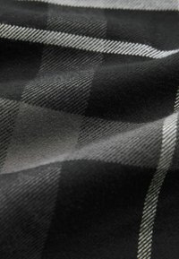 Kariertes Material in Schwarz- und Grautönen mit weicher Textur. Das Muster enthält karierte Quadrate und feine Streifen.