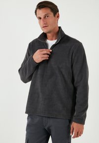 Dunkelgrauer Fleece-Pullover mit halbem Reißverschluss-Kragen, langen Ärmeln und strukturiertem Stoff; hat eine lockere Passform und einen geraden Saum.