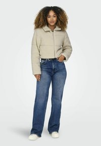 Beige fleece cropped jasje met een rits aan de voorkant, een hoge kraag en een textuurafwerking, gecombineerd met hoog gedragen blauwe denim jeans.