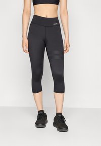 Mustad musta värvi spordikindaid, millel on kõrge vöökoht ja külgedel tekstuuriga aktsentmuster. Kandmise all mustad spordijalatsid.