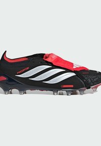 Μαύρο ποδοσφαιρικό παπούτσι με κόκκινες αποχρώσεις και υφή σχεδίου. Διαθέτει εφαρμογή που αγκαλιάζει το πόδι, ασημένιες ρίγες και διαφανές εξωτερικό πέλμα με τάπες για πρόσφυση.