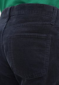 Παντελόνι από κορδόνι σε σκούρο ναυτικό μπλε με κάθετη ανάγλυφη υφή, με πίσω τσέπη και ζώνη μέσης με ραμμένες λεπτομέρειες.