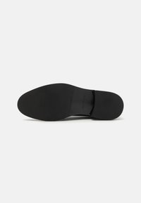 Black shoe sole with a smooth texture, slightly rounded shape, and minimal design features. No visible brand markings or patterns.