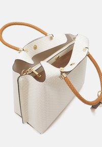 Sac à main blanc à texture tissée avec une forme structurée, poignée tressée marron, ferrures dorées et un dessus ouvert révélant un intérieur marron.