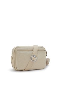 Beige rectangular crossbody bag made of textured material, with a zip closure, adjustable strap, and a pom-pom accent on the side.