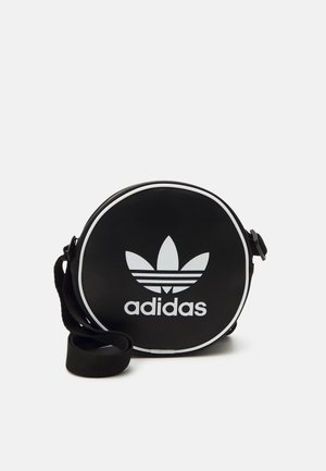 Sac à main noir rond en cuir synthétique texturé avec des accents blancs. Présente un logo Adidas blanc bien en vue et une bandoulière.