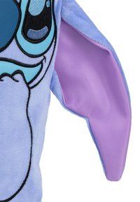 Jouet en peluche avec fourrure bleue, présentant de grands yeux expressifs et des oreilles intérieures violettes. Des contours noirs soulignent les traits du visage. Texture douce.