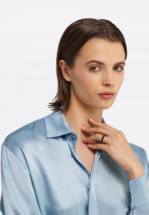 Light blue satin shirt with a buttoned collar, featuring a close-up of a hand wearing a black and gold ring against neutral background.