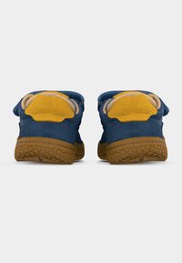 Πίσω όψη μπλε και κίτρινων casual παπουτσιών με υφή καφέ λαστιχένιων σολών σε λευκό φόντο.