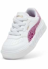 Fehér sneaker texturált lila kiegészítővel, perforált orral, lapos fűzőszerkezettel és vastag fehér talppal. Puma márkajelzés látható.