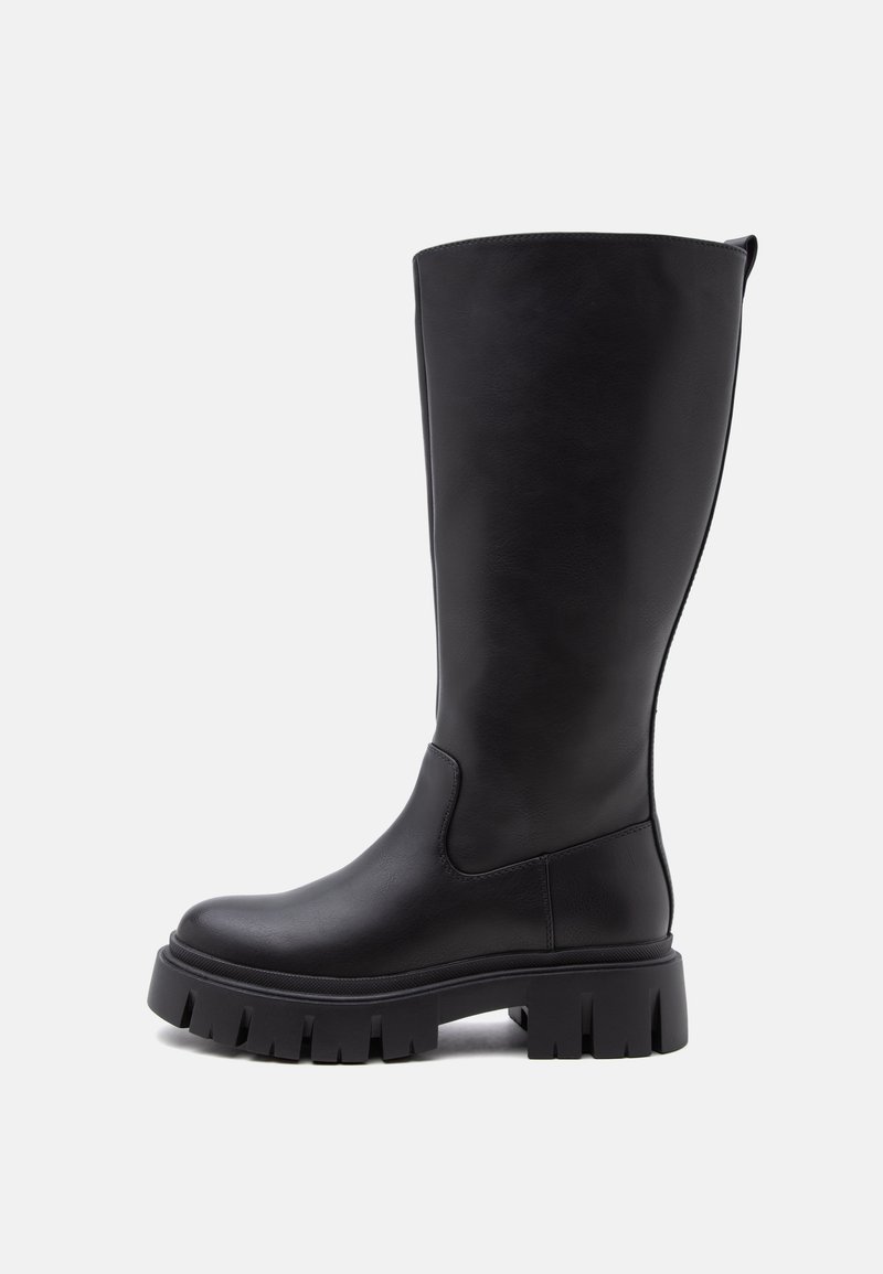 Ψηλό μαύρο δερμάτινο μπότες με παχιά σόλα με αυλάκια και στρογγυλεμένη μύτη, εμφανίζεται σε πλευρική όψη σε απλό ανοιχτό φόντο.