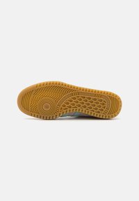 Adidas sneaker sole featuring a gum rubber bottom with a textured grip pattern and embossed logo, in earthy tones with teal accents.