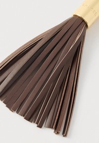 Pruun nahast tutt mitmete lukkudega, kinnitatud kuldse metallkorgiga, millel on graveeritud tekst. Sile tekstuur ja sujuv disain.