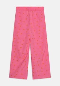 Rosa vide bukser med elastisk talje og store orange prikker på et teksturert stoff.