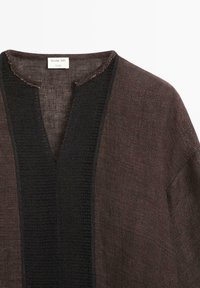 Bruine top met lange mouwen met een getextureerd zwart verticaal paneel en een ingezette halslijn, gelabeld Massimo Dutti Studio.