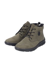 Bottines en suède vert olive avec des lacets noirs, bout rond, col rembourré et semelle en caoutchouc flexible. Emblème sur le côté extérieur.