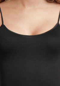 Black camisole top with thin straps, made of smooth, stretchy fabric. Features a scooped neckline and a form-fitting silhouette.