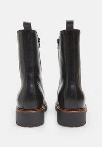 Botine negre din piele cu textură netedă, dotate cu un tab pentru a fi trase pe călcâi și cu fermoare laterale, având o talpă din cauciuc rezistentă cu un accent maro.