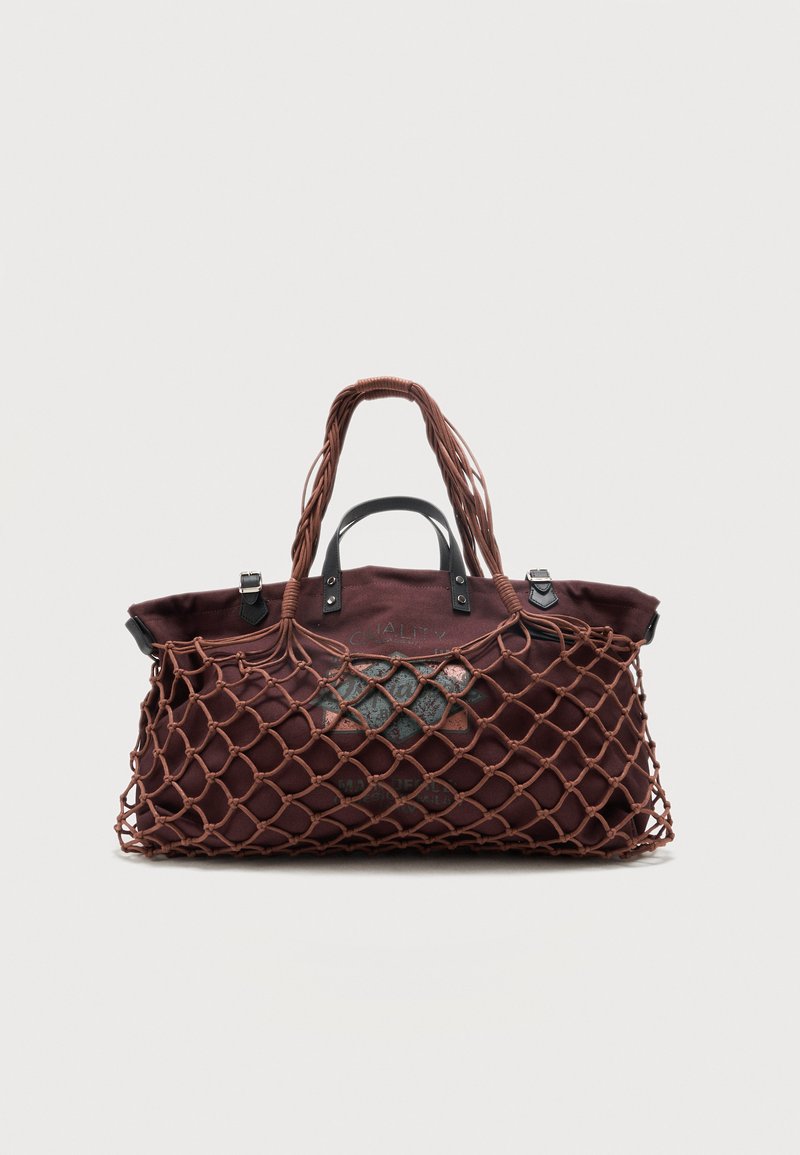 Sac fourre-tout en tissu marron à l'intérieur d'un sac en filet extérieur avec des poignées tressées, sur un fond clair uni.