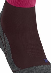 Ingrandimento di una calza con una parte superiore rosa, una sezione centrale marrone scuro con motivi testurizzati e una parte inferiore grigia con il marchio.