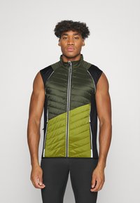 Ærmeløs vest med en quilted design i mørkegrønne og lyse olivengrønne paneler, med sorte sider, høj krave og lynlås.