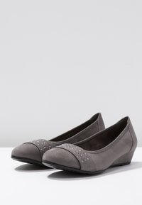 Scarpe con tacco a cuneo in suede grigio con punta arrotondata, caratterizzate da una tomaia testurizzata e una fila decorativa di strass lungo la parte anteriore.