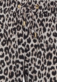Leopardprint broek in beige en zwart, met een trekkoord in de taille en gouden accenten, gemaakt van textuurrijke, lichtgewicht stof.