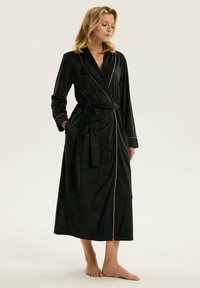 Czarna aksamitna szata z długimi rękawami, paskiem w talii i kieszeniami. Posiada kontrastowe różowe wykończenie wzdłuż kołnierza i krawędzi przodu. Długa długość.