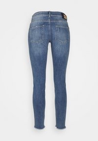 Slim jeans i medelblå denim med en fransad fåll, med två bakfickor och en logotyppatch på midjebandet.