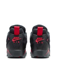 Baskets noires avec des accents rouges, présentant une surface texturée, un col rembourré et un onglet de talon proéminent affichant le logo Nike.