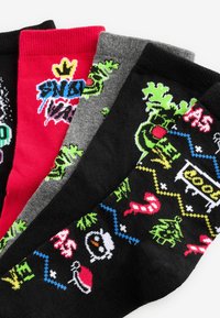 Fyra par strumpor i svart, grått, rött och multikolor. Varje par har unika grafiska mönster och texturer med lekfulla designer.