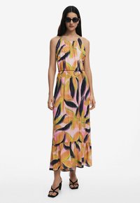Abito maxi con un design floreale in rosa, arancione e verde. Presenta una vita aderente con un dettaglio ad anello e un fondo a strati. Tessuto leggero.