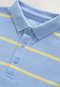 Camisa polo de color azul claro con una tela texturizada, que presenta dos franjas horizontales amarillas y cuatro botones azules en la tapeta.
