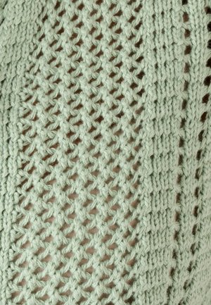 Primo piano di tessuto lavorato a maglia verde chiaro con motivi a diamante e coste verticali e trama traforata.