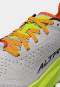Κοντινό πλάνο γκρι και νέον κίτρινο παπούτσι τρεξίματος με πορτοκαλί κορδόνια και διάτρητο επάνω μέρος, με το λογότυπο "ALTRA" στην πλευρά.