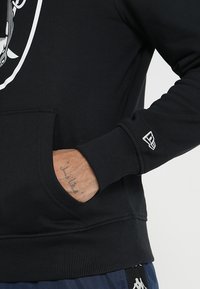 Felpa nera con cappuccio, polsini e orlo a costine, tasca anteriore a marsupio, con una stampa del logo bianca. Tessuto testurizzato con una vestibilità aderente.