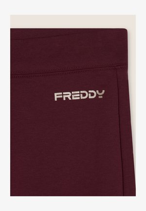 Leggings color bordeaux realizzati in un tessuto morbido ed elastico con una texture liscia. Presentano un logo argento "FREDDY" sulla vita.